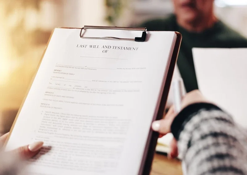 Close-up of a person holding a clipboard with a “Last Will and Testament” document during a meeting with a solicitor.